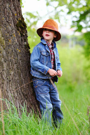 Happy smiling boy dressed in country style playing in the park near sunset with shallow depth of field and copy space to left and right の写真素材