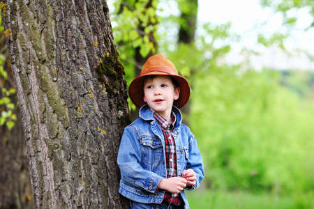Happy smiling boy dressed in country style playing in the park near sunset with shallow depth of field and copy space to left and right の写真素材