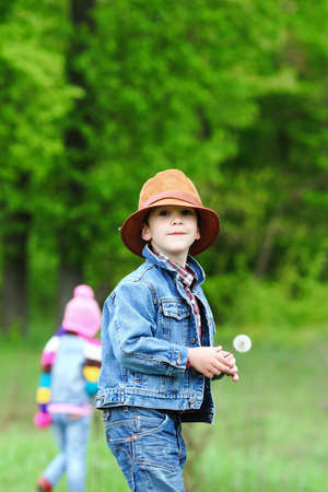 Happy smiling boy dressed in country style playing in the park near sunset with shallow depth of field and copy space to left and right の写真素材