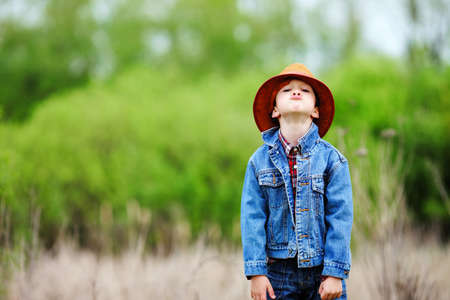 Happy smiling boy dressed in country style playing in the park near sunset with shallow depth of field and copy space  の写真素材
