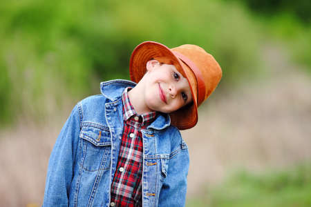 Happy smiling boy dressed in country style playing in the park near sunset with shallow depth of field and copy space to left and right の写真素材