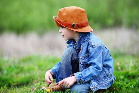 Happy smiling boy dressed in country style playing in the park near sunset with shallow depth of field and copy space to left and right の写真素材