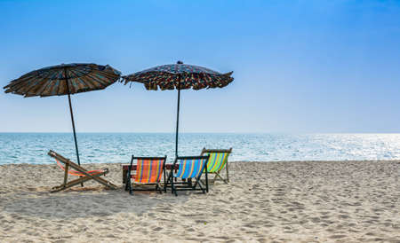 Beach chairs on the white sand beach with blue sky and umbrellas on the beach の写真素材