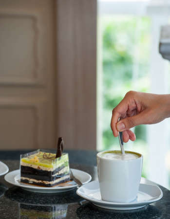 Close up hot coffee latte and coffee foam with cakeの写真素材