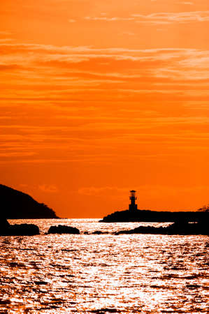 Beautiful seascape with silhouette lighthouse on sunsetの写真素材