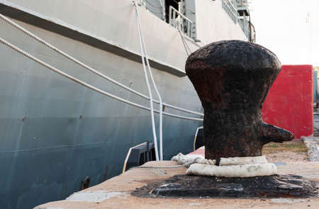 Old rusted mooring bollard with knotted nautical ropesの写真素材