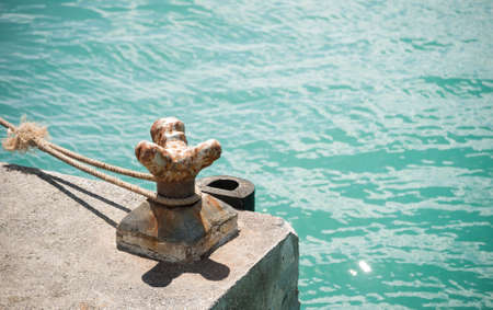 Old rusted mooring bollard with knotted nautical ropesの写真素材