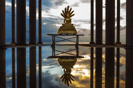 Buddha statue with reflection on water in the evening.