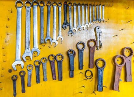 assortment of do it yourself tools hanging in a yellow wall