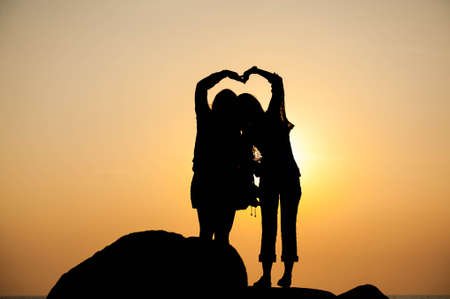 silhouette loving couple holding hands at beach during sunsetの写真素材