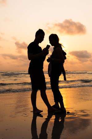 Silhouette of family on the beach at sunsetの写真素材
