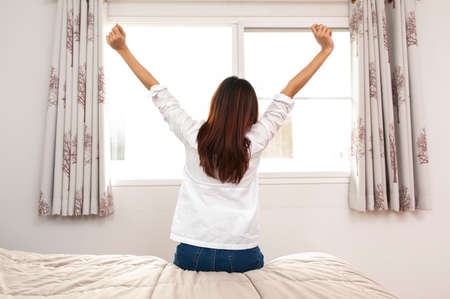 A asian Woman stretching in bed after wake up, back viewの写真素材