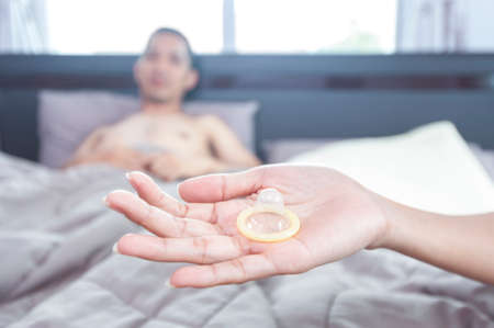 Young attractive couple in bed with a condomの写真素材