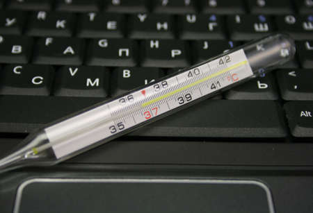 mercurial thermometer over laptop keyboardの写真素材