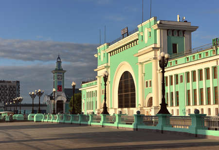 The facade of the largest railway station in Siberia in the style of constructivism in the morning contrasting light, a deserted square, a large arched window, blue sky, clouds, a tower in the distance. Novosibirsk, Russia, 2020の写真素材