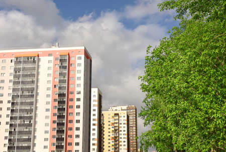 Multi-storey new houses in a row, green foliage of trees, blue sky with white clouds. Novosibirsk, Siberia, Russia, 2020の写真素材