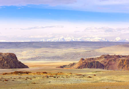 Chui Valley in the Altai Mountains. Rocky cliffs, a rolling plain in the distance against the snowy...