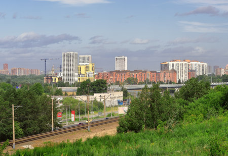Novosibirsk, Siberia, Russia - 06.20.2020: Construction of the "European Bank" district on the Bank of the Ob river, multi-storey high multi-colored houses, railway, blue sky with clouds in summerのeditorial素材