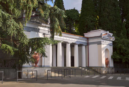 Nikita village, Crimea, Russia - 05.07.2019: White portico - Propylaea - entrance to the Botanical garden. Doric columns, vases in niches. Drowning in greeneryのeditorial素材