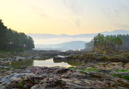 Manzherok rapids in the Altai Mountains. Dawn over the rocky bank of the Katun River, the village of...
