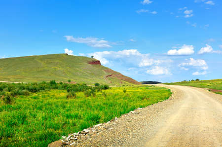 Green hills in summer under a blue cloudy sky. Siberia, Russia