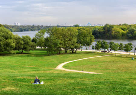 Moscow / Russia-09.03.2020: Park Kolomenskoe in summer. The girl in the meadow on a green slope that...