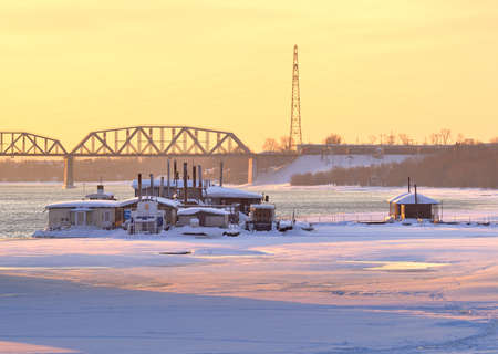 NOVOSIBIRSK, Siberia, Russia-02.07.2021: Frozen bank of the Ob River, floating pier on the background of the railway bridge in the morning lightのeditorial素材