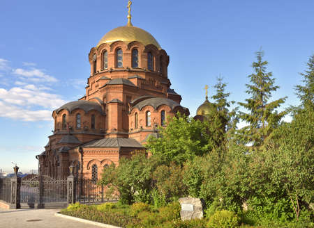 Alexander Nevsky Cathedral in Novosibirsk. Orthodox Church in the Russian-Byzantine style of red brick with gold domes. Monument of architecture of the late xix century. A new chapel in the courtyard of the temple, without people, blue sky, a place for text. Novosibirsk, Siberia, Russia, 2020の写真素材
