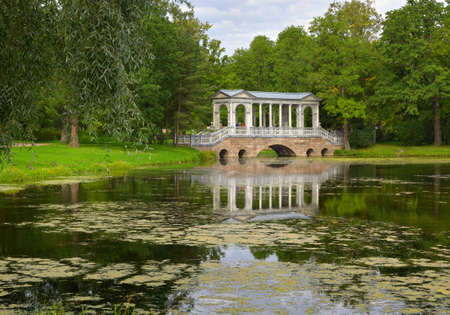 Pushkin / Saint Petersburg / Russia-09.03.2020: Marble bridge. Garden pavilion on the Bank of the Big pond of the Catherine Park among the lush foliage of trees. Monument of Russian architecture of the XVIII centuryのeditorial素材