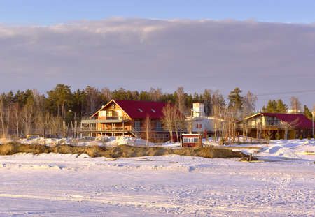 Novosibirsk, Siberia, Russia-04.03.2021: Houses on the shore of the Ob Sea. Wooden house with a red roof among snowdrifts on a frozen beachのeditorial素材