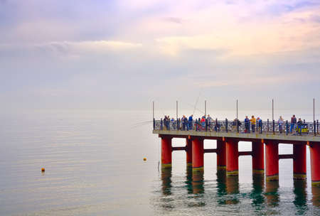 Adler, Sochi, Russia, 11.01.2021. People on the sea pier. Vacationers and fishermen on the Black Sea coast in autumnのeditorial素材