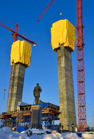 Novosibirsk, Siberia, Russia, 01.29.2022. Construction of the pillars of the Central Bridge. Monument to Emperor Alexander III on a construction site with high cranesのeditorial素材