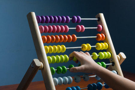 Abacus with colorful beads on blue background, close up, Counts kids learning, kids math class concept, with counting child handsの写真素材