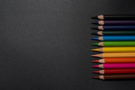 Set of colored pencils, row of wooden colored pencils on black background. colored pencils for drawing. pencils arranged in rainbow colors, colorful, copy space.の写真素材