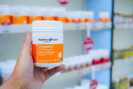 Jakarta, Indonesia, february 16, 2022: hand is holding ester c, enervon c, pharmaton, vitamin c effervescent tablets to increase endurance, with a background in medicine productsのeditorial素材