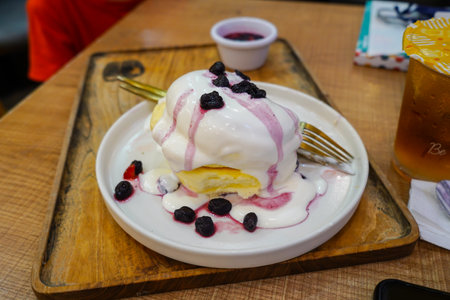 Homemade Fluffy Japanese Pancakes with berry sauce and ice cream topping on a white plateの写真素材