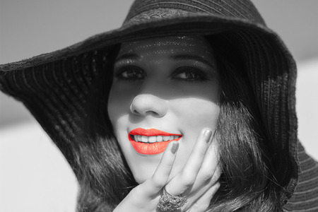Portrait of smiling beautiful young woman with wonderful skin texture  in  black raffia hat. Trendy fashion turquoise smoky eyes makeup. Sensual red  lips. Black white photo.  Model shooting on the beach. Hippie. Boho-chic.の写真素材