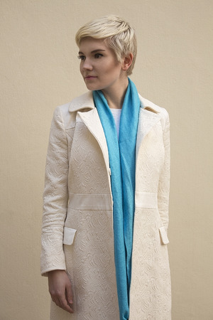 Stylish beautiful young woman blonde wearing blue scarf and white pattern coat isolated on beige background. Girl with short hair. Professional nude makeup. Fashion fresh make-up. Model shooting. Elegant style.の写真素材