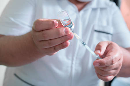 closeup  hands holding a syringe and liquid background.の写真素材