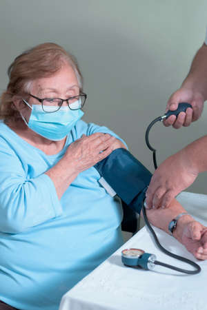 older adult latin woman in a test to measure her blood pressure as a prevention measure