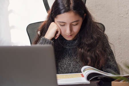 Hispanic Latino teen girl woman takes distance classes online with her teacher sheltering at home