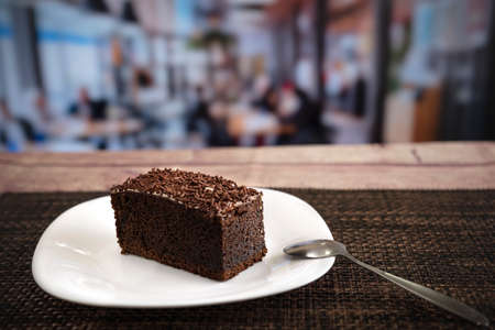 slice of chocolate flavor cake with chocolate chips on wooden table in a restaurant
