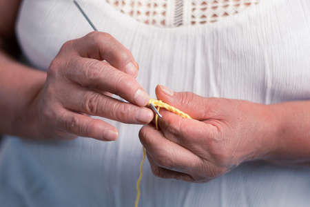 elderly woman 60 year old latin grandmother knitting happy and comfortable inside her home