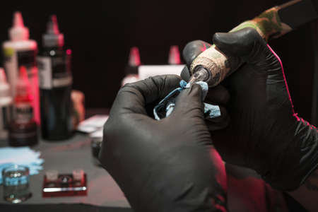 Latin person tattooing arm, with adequate security measures in his workplace happy and calm comfortable in his chairの写真素材