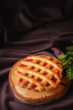 tartlet or tart filled with homemade delicious strawberry jam on a brown wood and cloth for a snackの写真素材