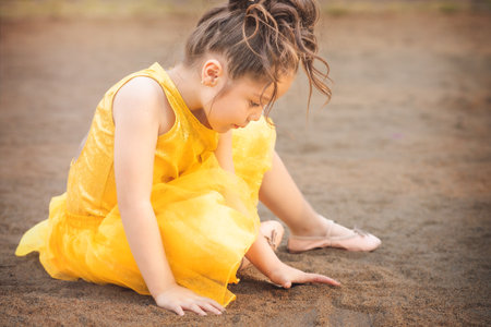 beautiful junior little girl playing in the park in yellow dress laughing with bubbles, screaming with happiness in family enjoying children's dayの写真素材