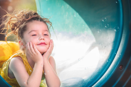 beautiful junior little girl playing in the park in yellow dress laughing with bubbles, screaming with happiness in family enjoying children's dayの写真素材