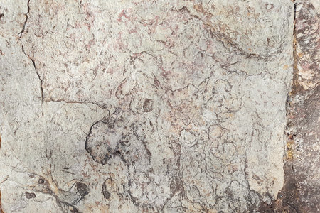 Background of stone wall with cracks, stains and seams, with unpolished marbled effect, in beige colorの写真素材
