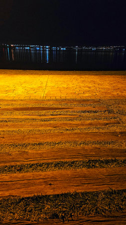 deck at night on the edge of the lake with wooden planks and orange coloring due to city lightの写真素材