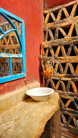 rustic bathroom sink, with red wall and mirror with blue frame, next to orchid pendant and brick wallの写真素材